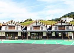 青空と山をバックに写る3つの館が並んだ湖東三山館あいしょうの写真