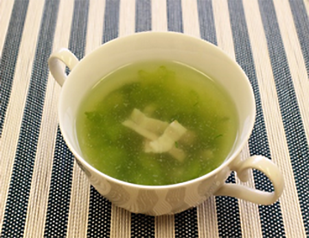 白いスープカップに注がれたグリーン色がきれいなセロリのスープの写真