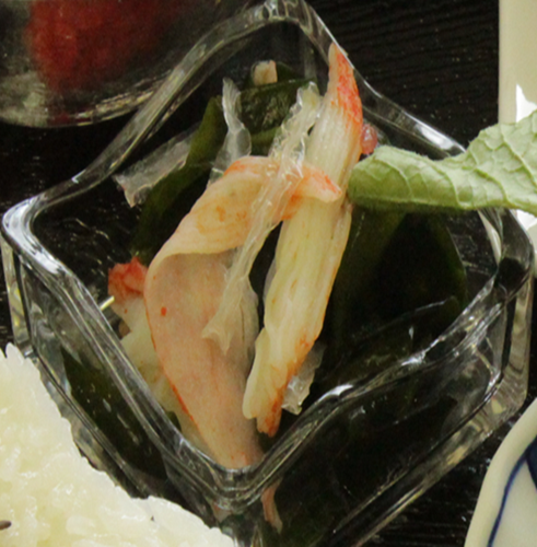 ガラスの器に盛られた海藻サラダとかにかまの酢の物の写真
