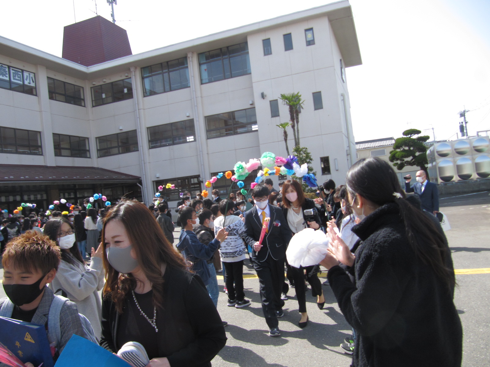 在校生が作った花道を通って学校を出る卒業生と保護者