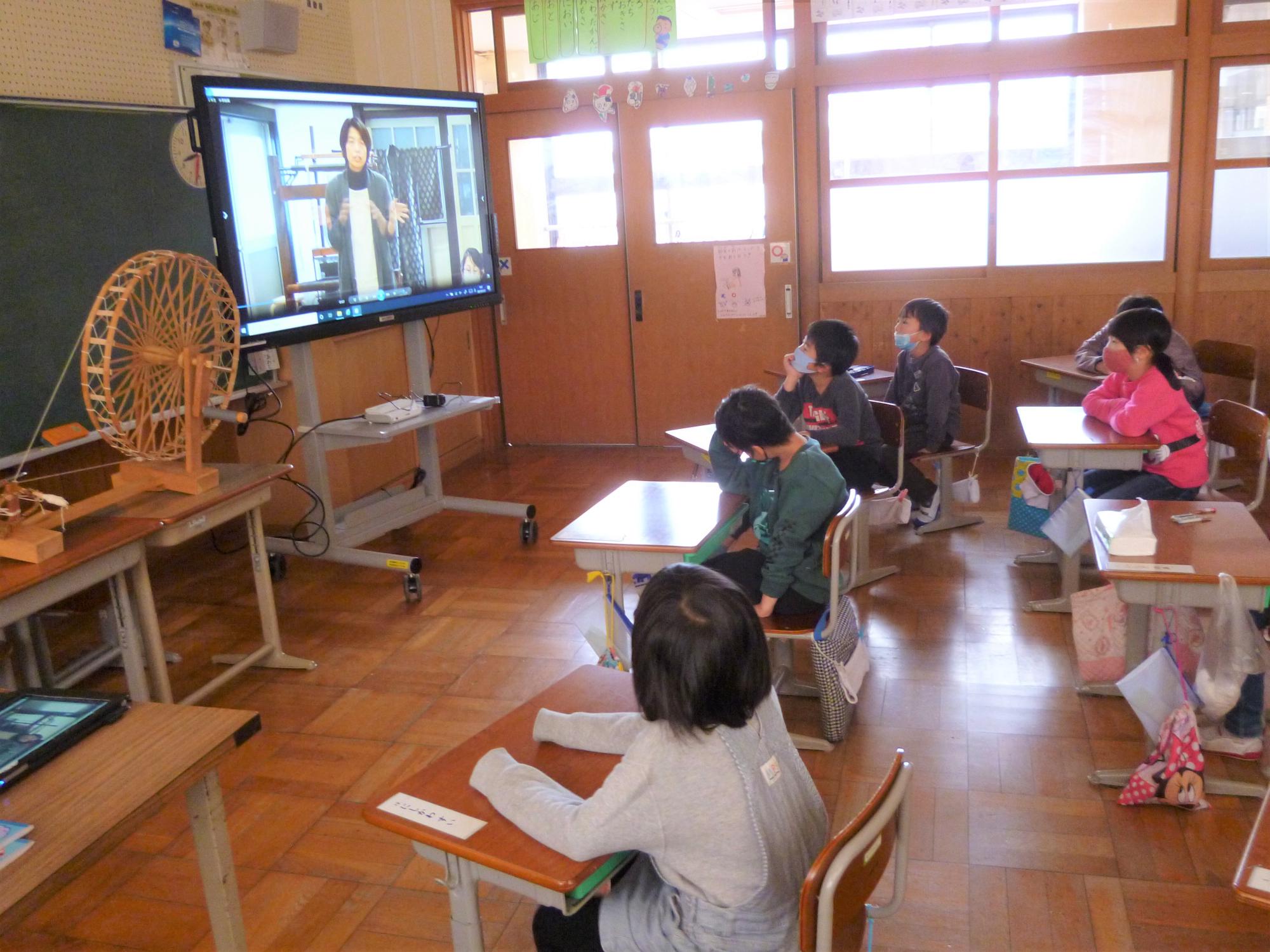 教室でビデオから流れる説明を見る児童たち