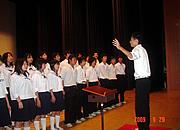 指揮に合わせて合唱をしているクラスの写真