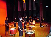 舞台上で10名ほどの生徒が太鼓の演奏を披露する前の写真