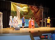 衣装を身に付け大きな幕の前で演劇をしている写真