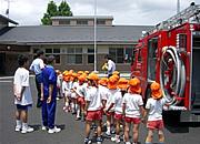 たくさんの幼稚園児と消防車の前で話を聞いている写真