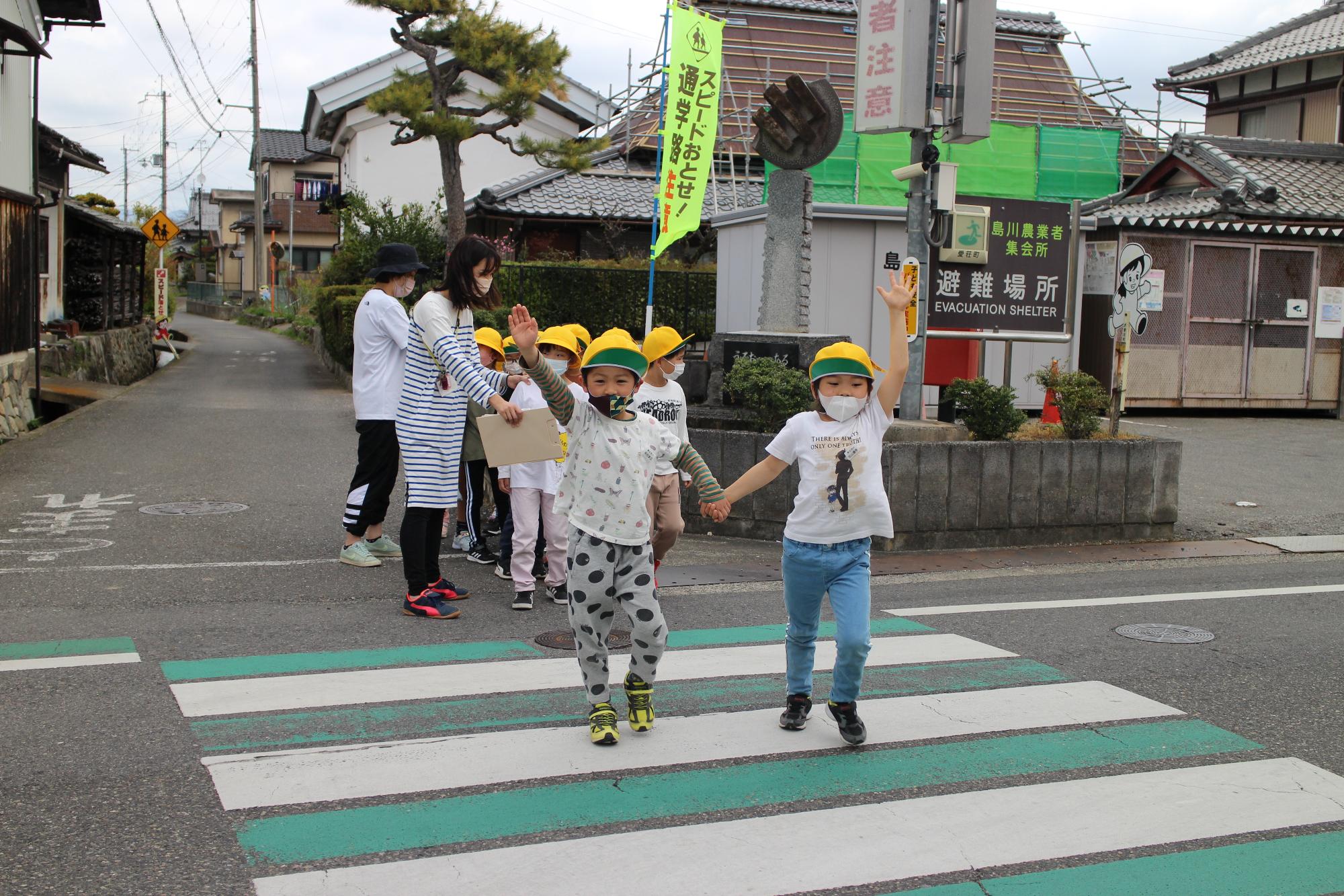 手を挙げて横断歩道を渡る子どもたち