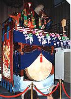 人形や幕などで鮮やかに装飾された太鼓を展示している写真