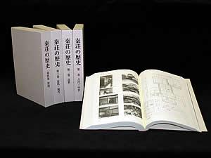 4冊が立てて置いてあり1冊が開いて中が見えるように置いてある『秦荘の歴史』第四巻の写真