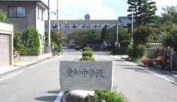 愛知中学校を背景に数メートル手前の通学路に置かれている愛知中学校と彫られた石板の写真