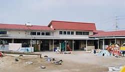 広い敷地に砂場と遊具がある赤い屋根の秦川愛児園の写真