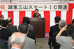 紅白幕の前で挨拶をしている嘉田滋賀県知事と記念行事に参加している人達の後ろから撮った写真